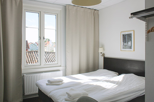 Bild på ett fräscht hotellrum i vitt med en svart säng